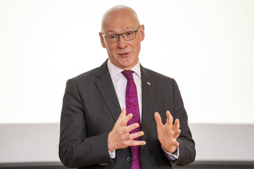 John Swinney speaking in public against white background