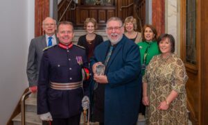 John Watson receiving award from Stephen Leckie watched by group of people in Perth Civic Hall