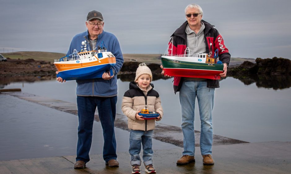 Image shows: A great-grandfather (left), grandfather (right) and their grandson, (centre) showing off their model boats at Cellardyke tidal pool.