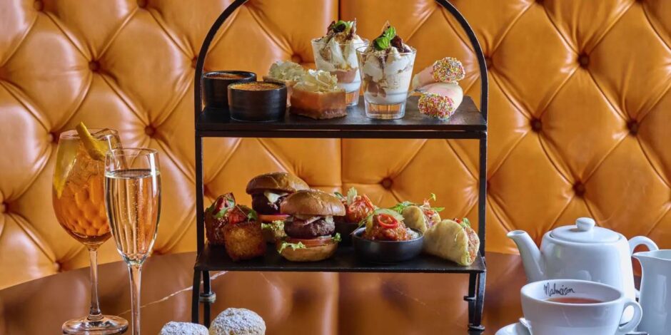 A cocktail, a flute of bubbly, afternoon tea treats and a pot of tea against the bright orange seats of the Malmaison.