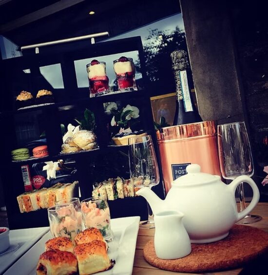 Pastries, prawn cocktail, a teapot and a bottle of prosecco laid out for afternoon tea at The Post House Coffee Co.