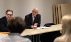 John Swinney at table listening to people seated in front of him