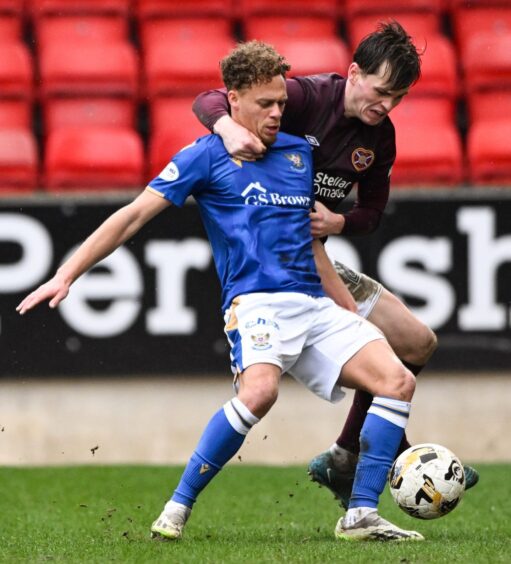 Stephen Duke-McKenna being held back by a Hearts defender.