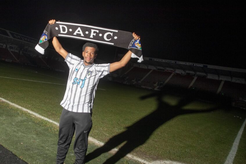 Taylor-Clarke at East End Park holding up a Pars scarf at night, after his arrival late on transfer deadline day