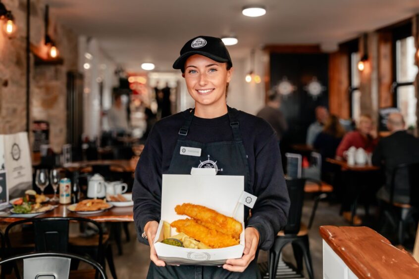 a waitress holding fish and chips