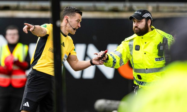 Referee Nick Walsh hands the vape to a police officer during the match. Image: Ross Parker/SNS Group