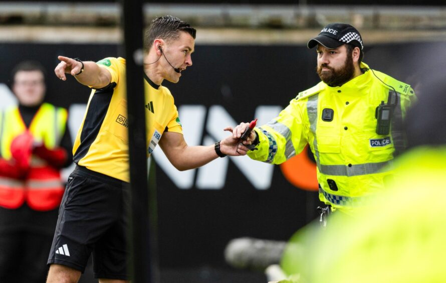 Referee Nick Walsh hands a missile that was thrown on to the pitch to a police officer during the Dundee derby. Image: Ross Parker/SNS