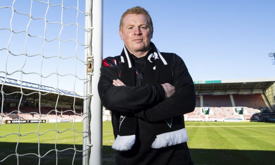 Neil Lennon leans against a goalpost wearing a Dunfermline Athletic scarf.
