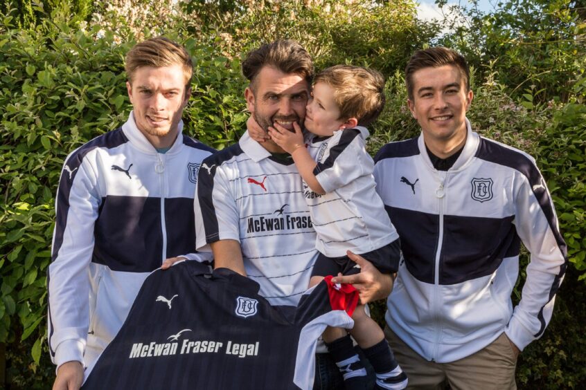 Dundee FC players Craig Wighton and Cammy Kerr present Billy Westwood and his young son Theo with new shirts