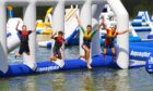 Four kids dive off an aqua park obstacle.