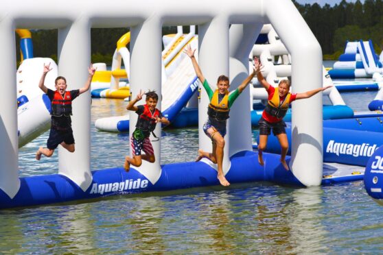 Four kids dive off an aqua park obstacle.