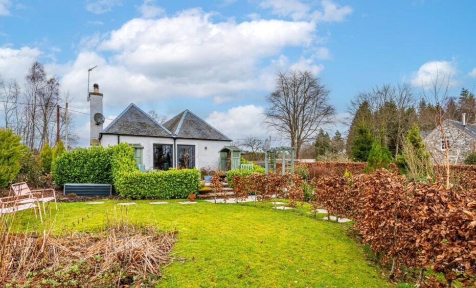 The garden features mature trees, beech hedging and a lawn.