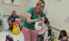 Kirsty Ross and families having fun with a bubble machine at Baby Sensory Stirling