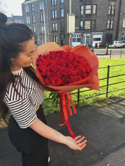 woman holding a bouquet of red roses