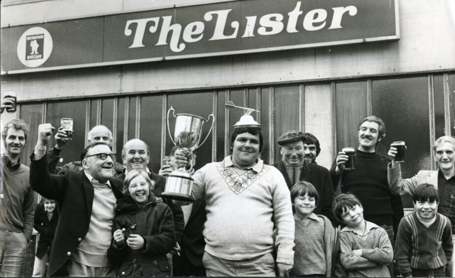 Members of the public join Jocky Wilson as he shows off the world championship trophy outside the Lister Bar in 1982. 