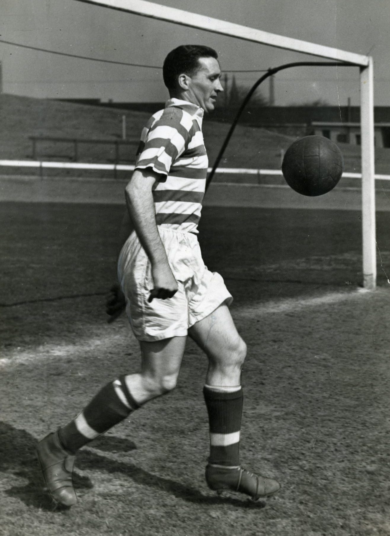 Jock Stein wearing a Celtic kit and kicking a ball in a goalmouth in 1954