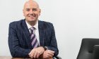 Aberdein Considine Perth boss Charlie Fraser sits at desk in his Perth office