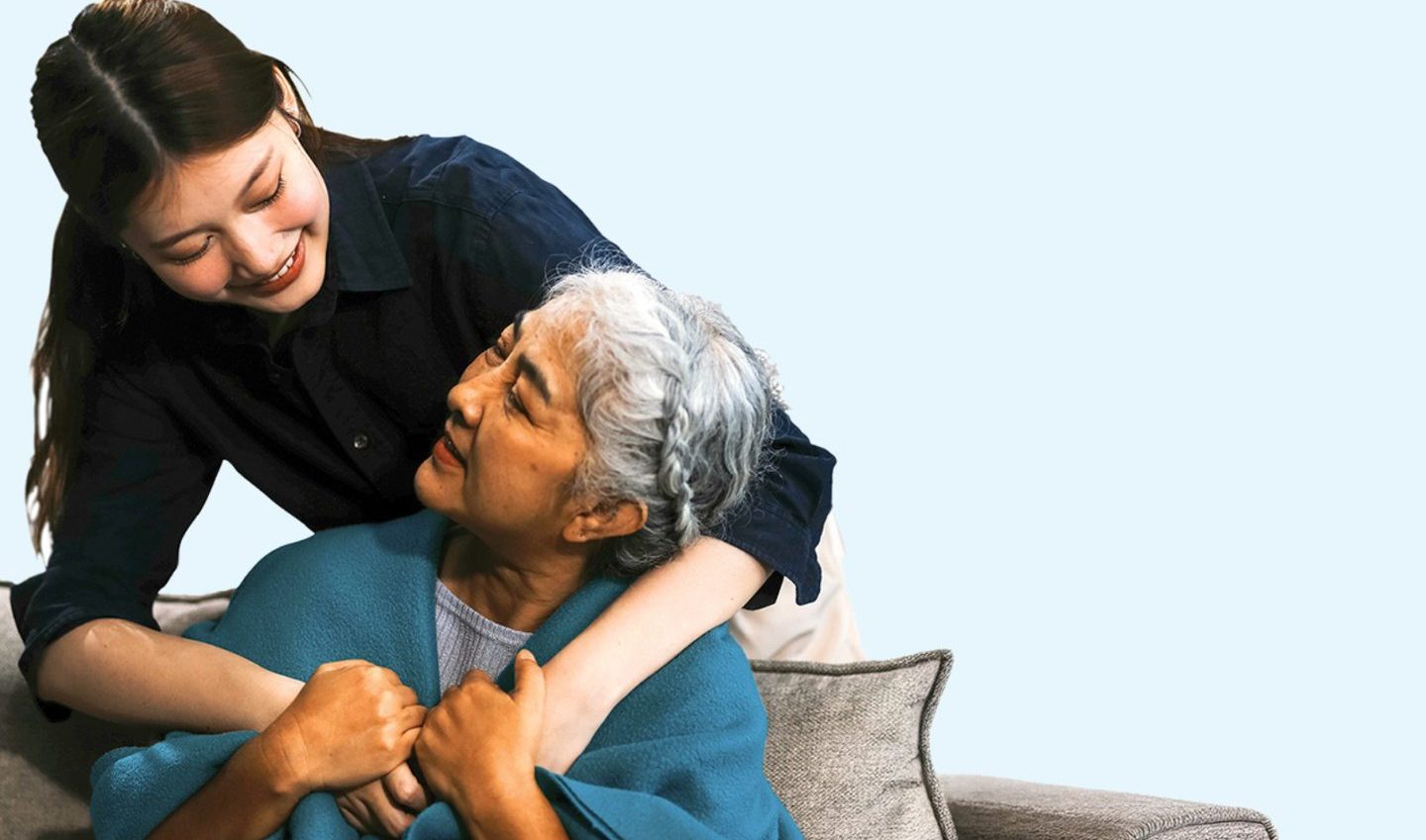 Carer with arms round elderly woman