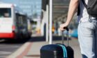 passenger holds on to his luggage as he waits for bus service to Edinburgh Airport