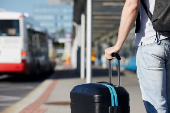 passenger holds on to his luggage as he waits for bus service to Edinburgh Airport