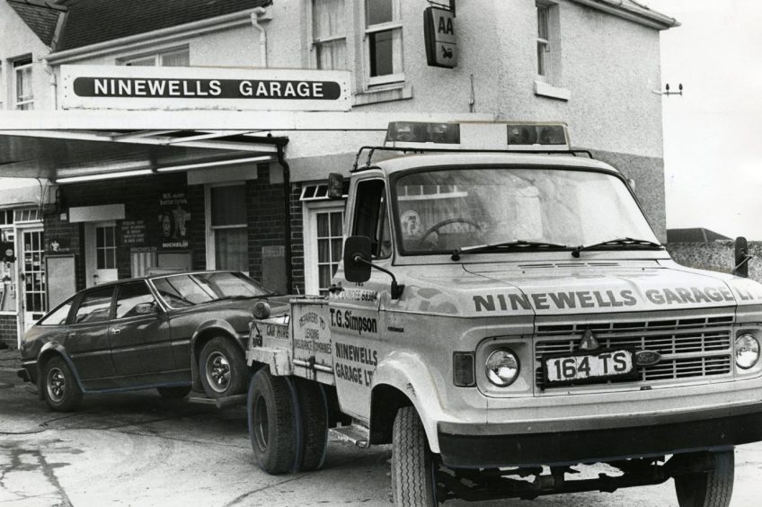 a car hitched to the back of a tow truck on the forecourt at Ninewells Garage