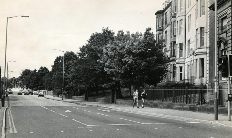 A view looking west down the Perth Road, with two joggers on the pavement. 