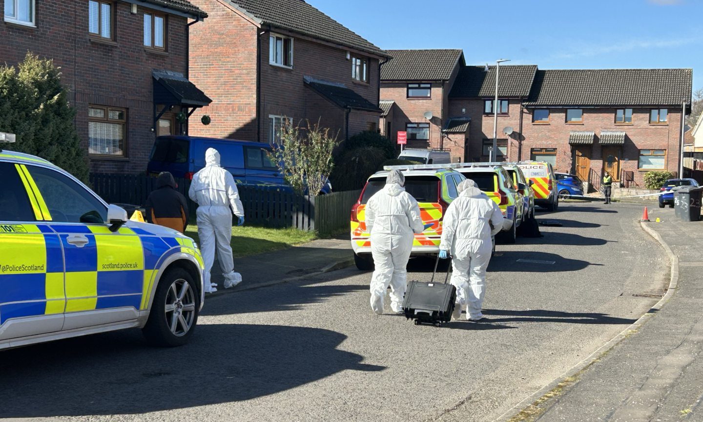 White suited forensic officers continue to assess the scene on Saturday.