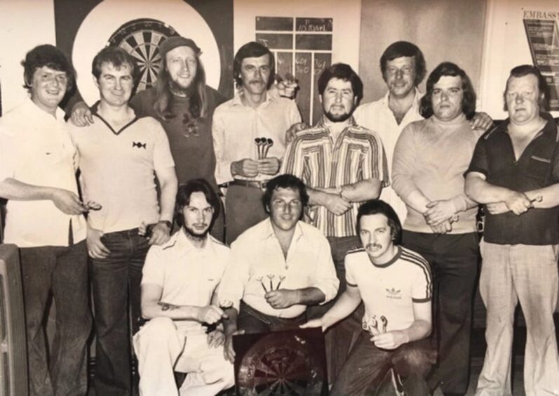 Jocky and his Alpha Bar team mates pose for a picture in front of a dartboard in 1978