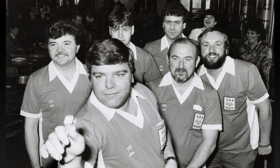 Jocky Wilson prepares to throw a dart, watched by his Scotland team-mates in 1985.