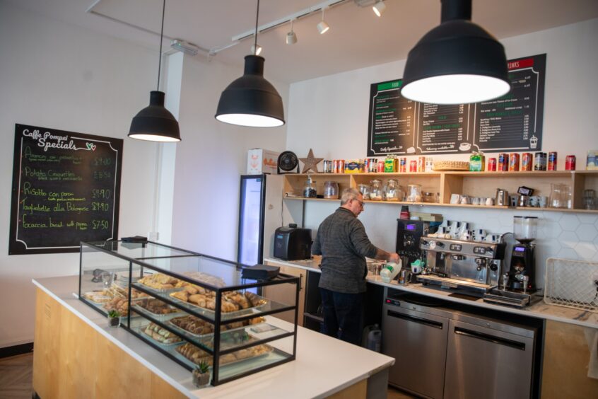 Image shows: a general view of the counter area at Caffe Pompei, with owner Mario Celiberti preparing a coffee in the background.