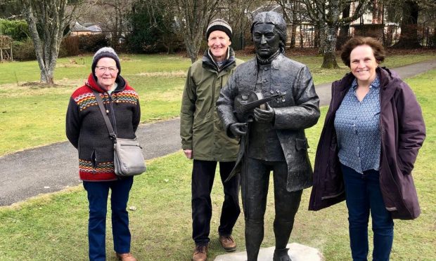 Three people standing beside Niel Gow statue in Dunkeld