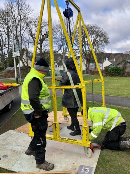 Niel Gow statue being placed by two men with metal machinery around it