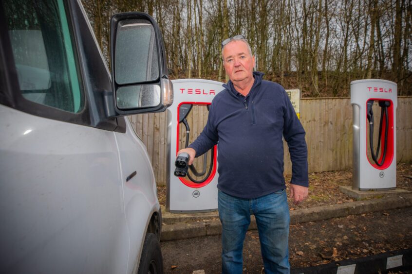 Ally Thomson, van driver, holding cable attached to Tesla charger