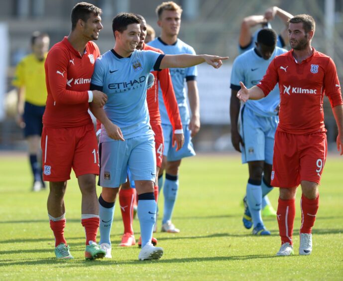 Dundee FC and Manchester City FC players on the pitch after the game
