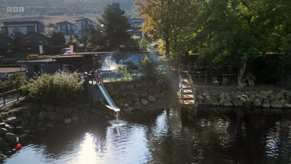 Flat roofed spa buildings with slide leading into Loch Tay