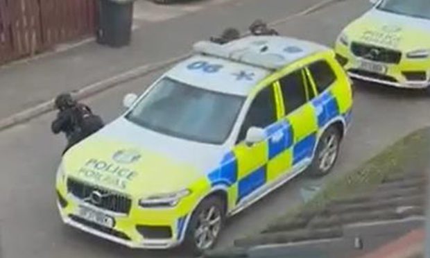 Police could be seen pointing their guns at a house during the stand-off on Earlston Avenue, Dundee. Image: Facebook