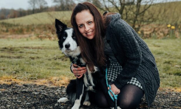 Laura Findlay crouching to cuddle border collie Harris