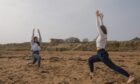 Jana Greig leading Poppy Watson through a yoga class on Kingsbarns Beach. Image: Rick Booth