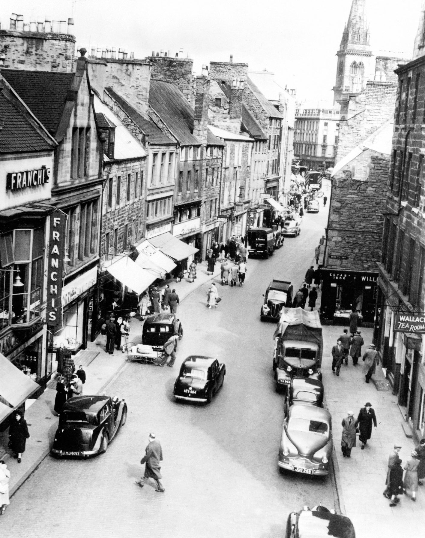 an aerial view showing people, cars and shopfronts at The Overgate in Dundee in April 1954.