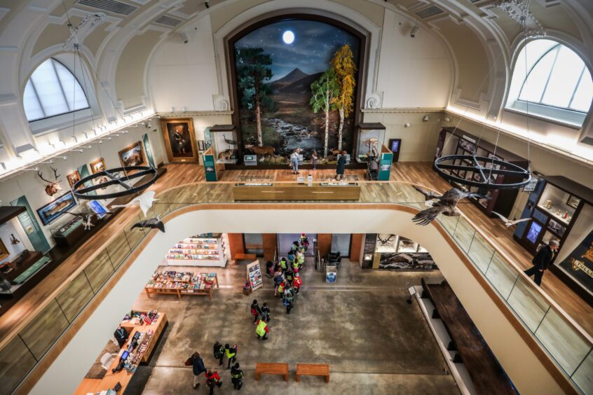 View of Perth Museum from up high showing first floor balcony and open space on ground floor with visitors walking around exhibits