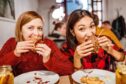 two girls enjoying burgers in a restaurant