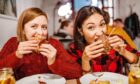 two girls enjoying burgers in a restaurant