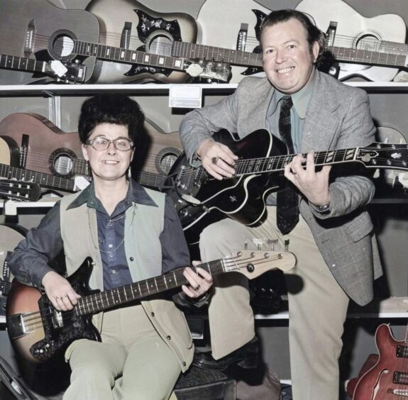 Husband and wife singing duo Vince and Eleanor Chalmers holding guitars in March 1975.