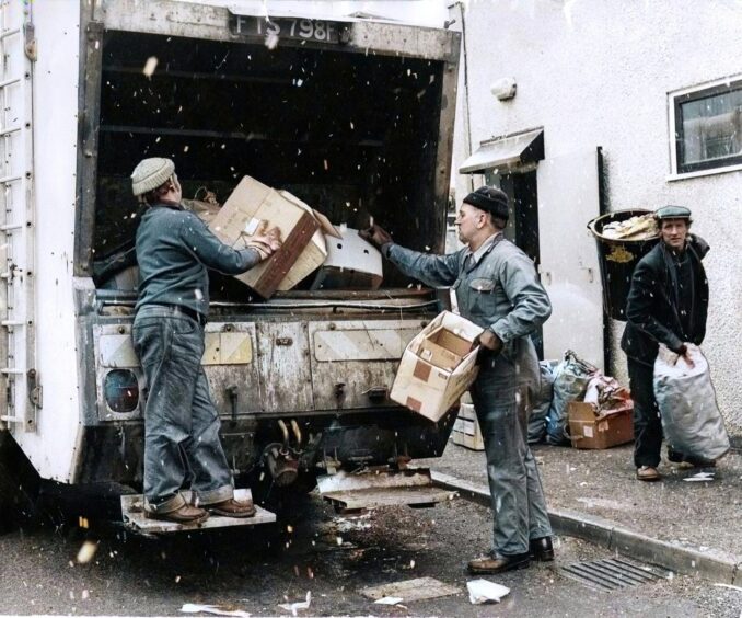 Bin men put rubbish in the back of a bin lorry