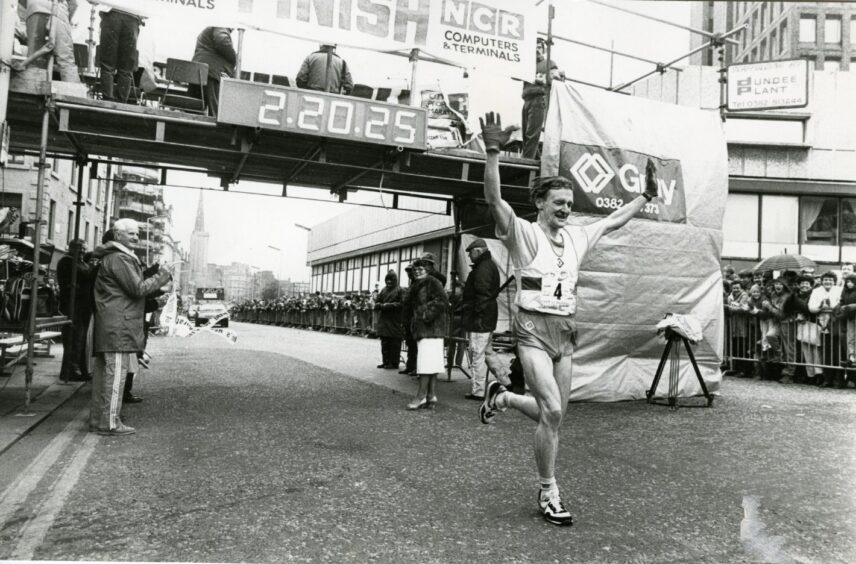 Murray McNaught with his arms in the air after he crosses the finish line and wins the Dundee marathon. 