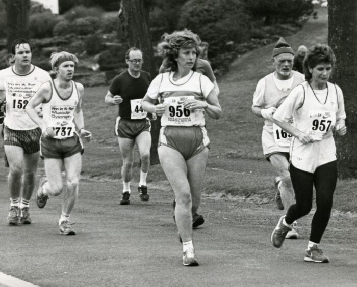 Competitors running on a tarmac path inside a park