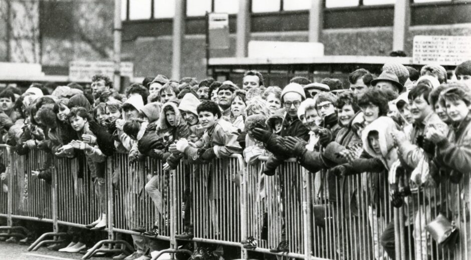 Crowds lining a barrier cheer on the runners in the Dundee marathon.
