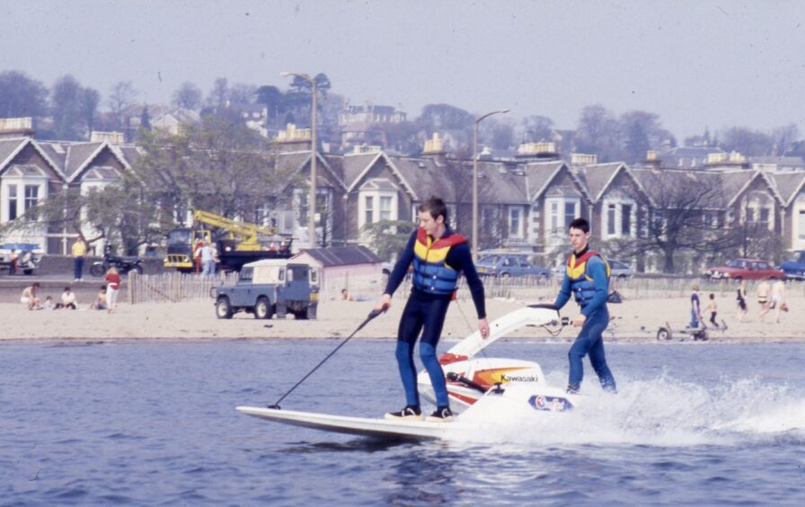 people on the beach as two youngsters enjoy some water skiing in the sunshine at Broughty Ferry