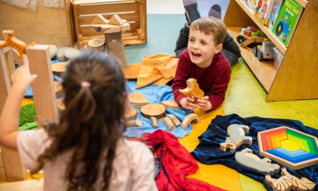 Boy laughing as he plays on floor in Psychology Kindergarten