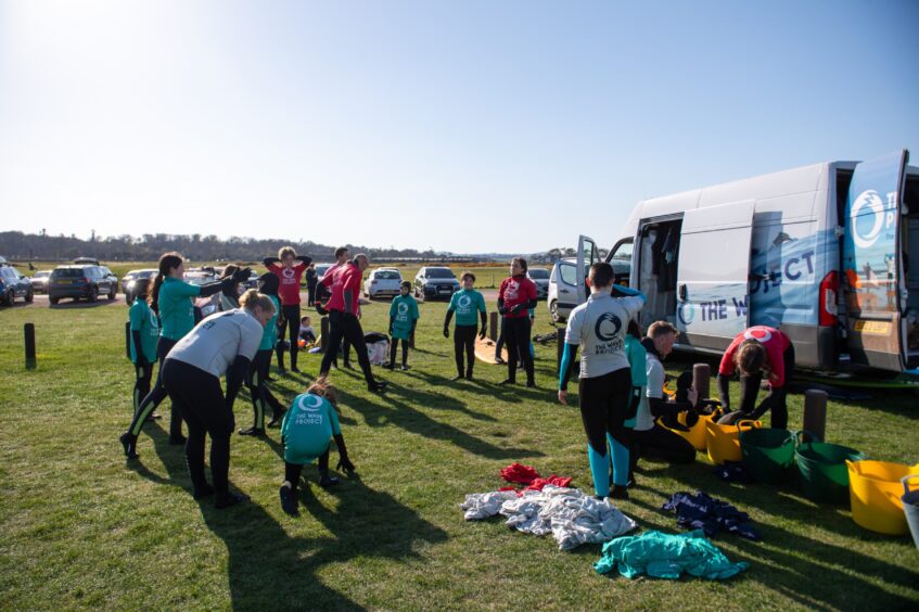 Image shows: Wave Project Surf Therapy participants and volunteers and instructors getting reading for a session in the waves at West Sands in St Andrews.